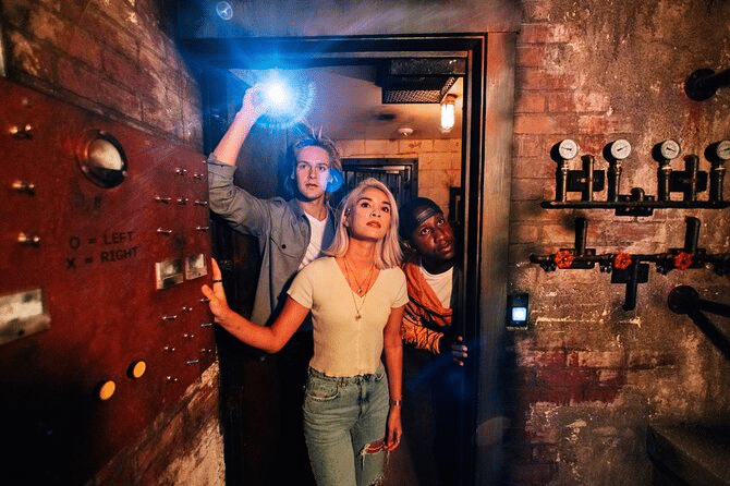 Three people exploring an escape room, using a flashlight to search for clues